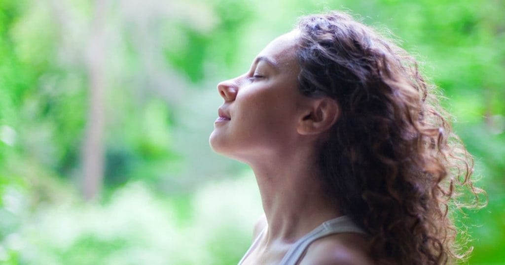 Woman with clear skin, looking up and practicing mindful breathing.