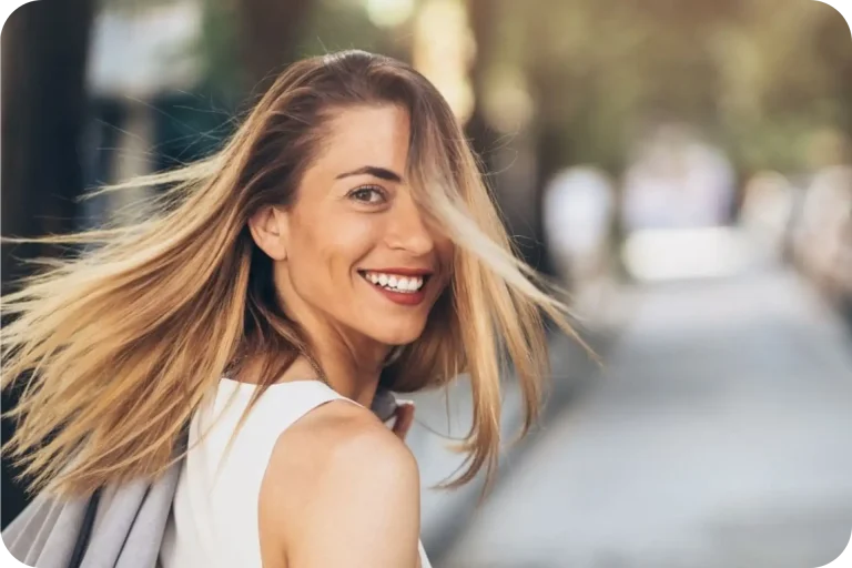 Confident woman smiling with wind in her hair, feeling free and empowered after overcoming addiction