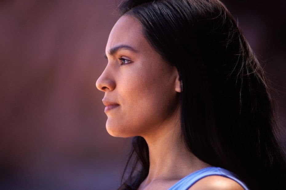 A person in side profile with a neutral expression in soft natural light.