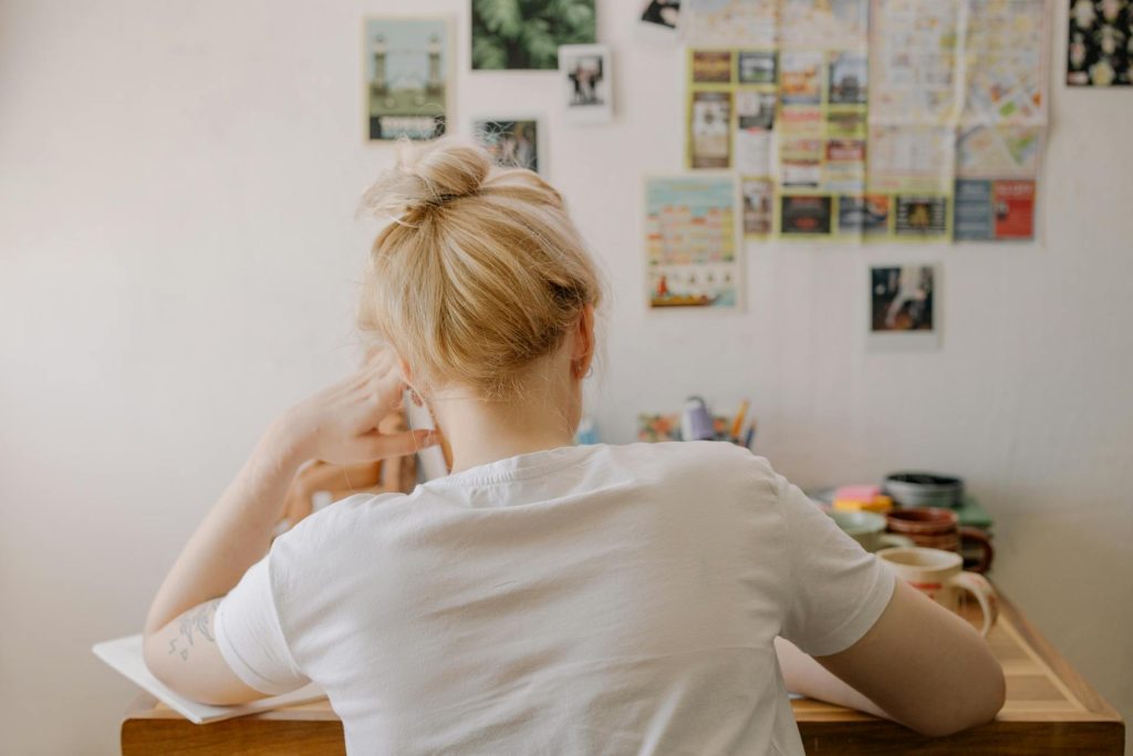 Person sitting at a desk with their back to the camera in a softly lit room, with no identifiable features