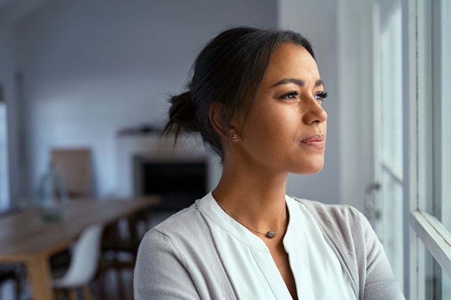 A calm woman gazing out of a softly lit window, capturing the sense of clarity and emotional ease that comes from releasing unfair guilt through RTT hypnotherapy.