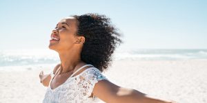 Woman standing outdoors with arms open and eyes closed, symbolising calm, confidence and freedom after quieting the inner critic.
