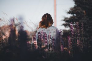 Woman standing among wildflowers at dusk, symbolising calm reflection and emotional renewal