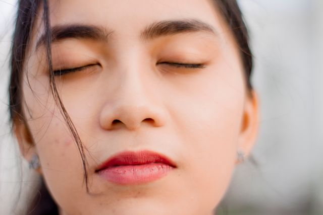Close-up of a woman's face with her eyes gently closed, reflecting a moment of stillness and calm